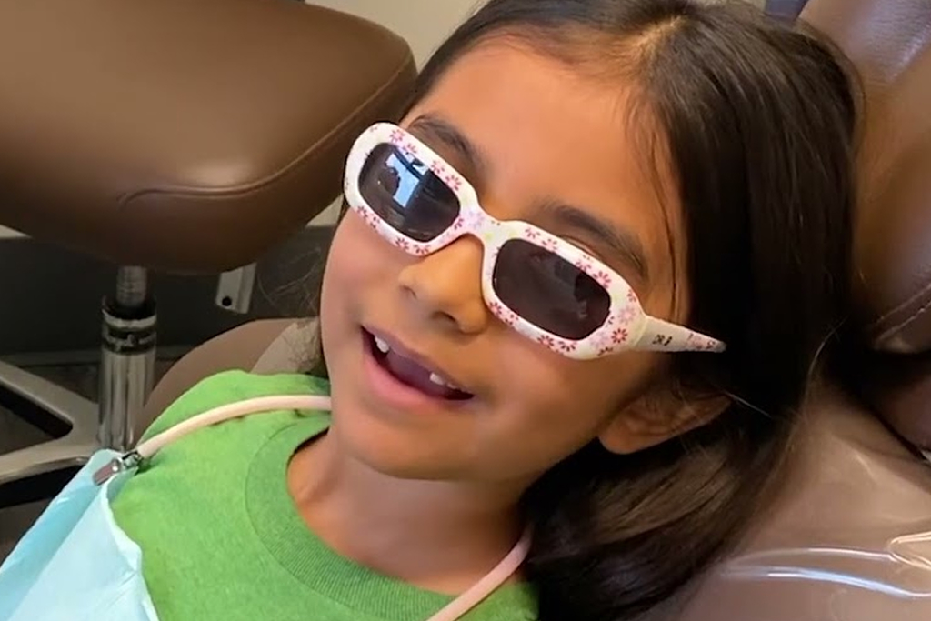 A gils in a glasses is smiling